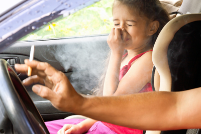 Hypnotherapist in Chester and Colwyn Bay young girl holding her nose in car seat whilst parent smokes in the car