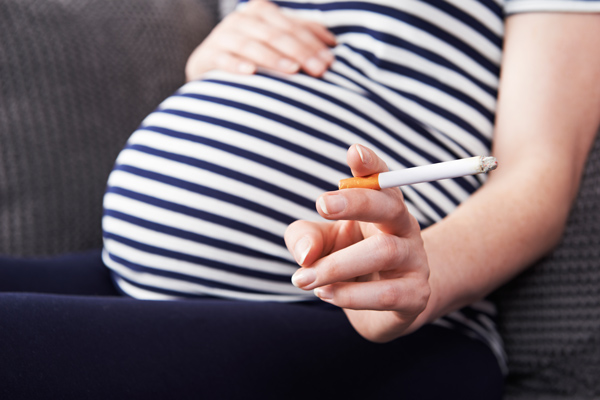Hypnotherapist in Chester and Colwyn Bay woman's pregnant belly and hand holding a cigarette