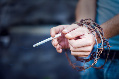 Hypnotherapist in Chester and Colwyn Bay hands wrapped in barb wire whilst holding cigarette